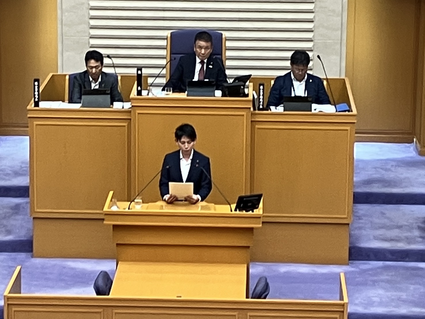 議場の演壇で、資料を手に発言する吉村だいき